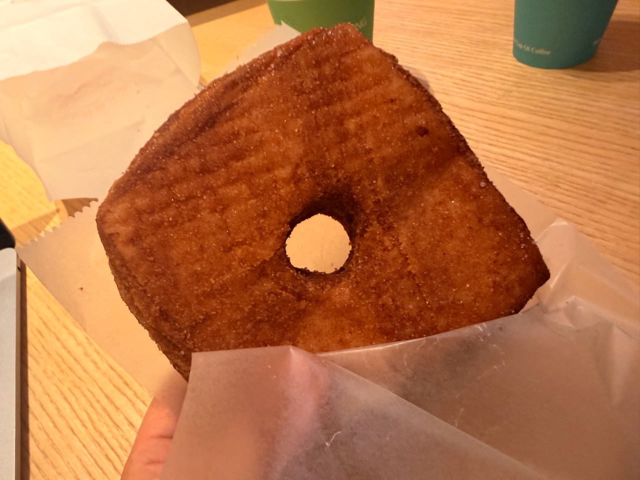 紙袋から取り出した、真ん中に穴のある四角いドーナツ