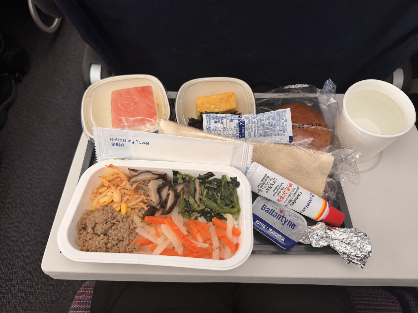 大韓航空の機内食のビビンバ。もやしやきのこ、青菜、ひき肉などが並び、横にはチューブ入りのコチュジャンが添えられている