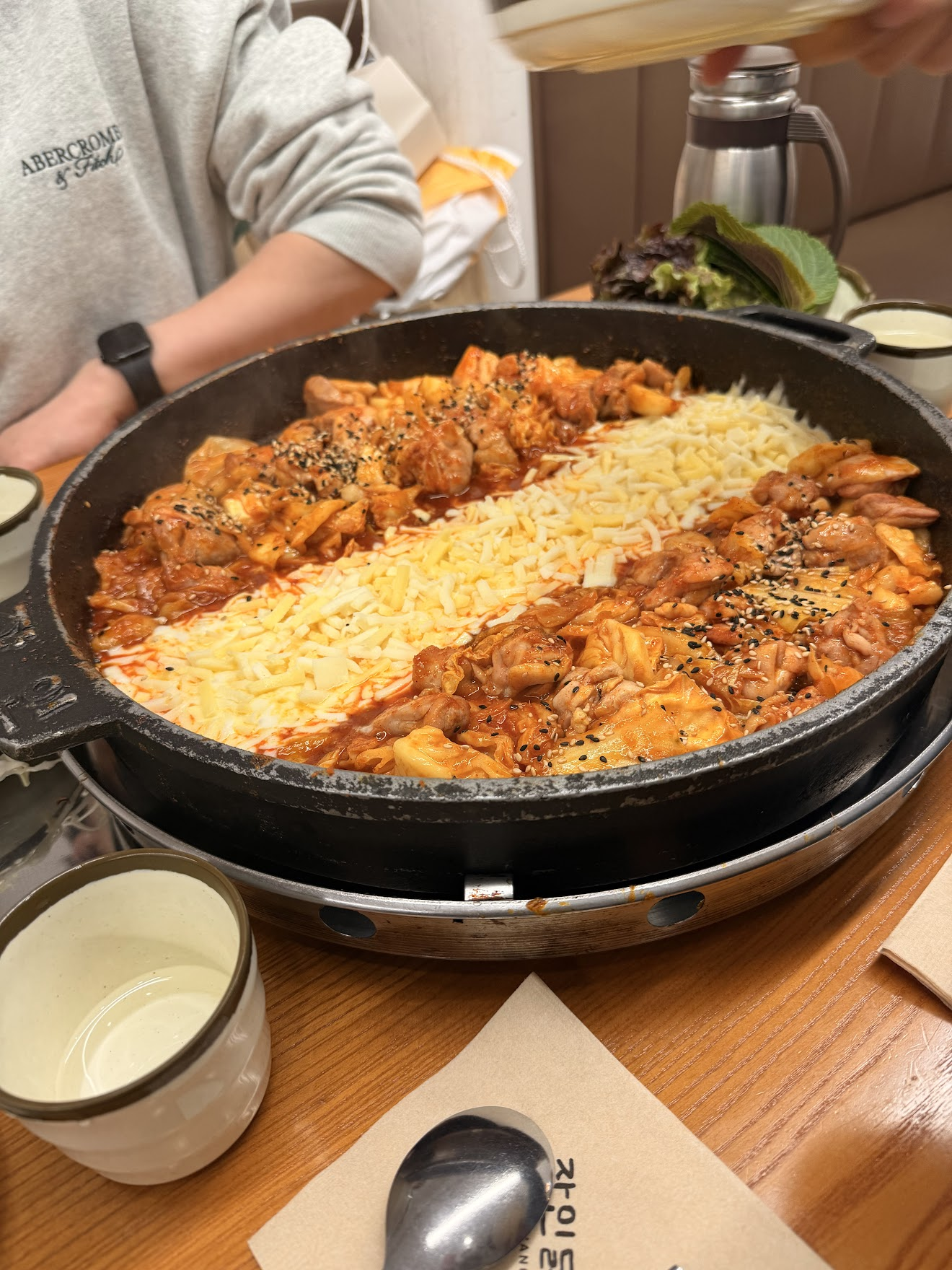 大きな鉄板の上で赤いヤンゲムソースに絡んだ鶏肉の間にとろーりチーズが溶けているチーズダッカルビ。ゴマがふりかけられ、旅行中一番辛かった一品