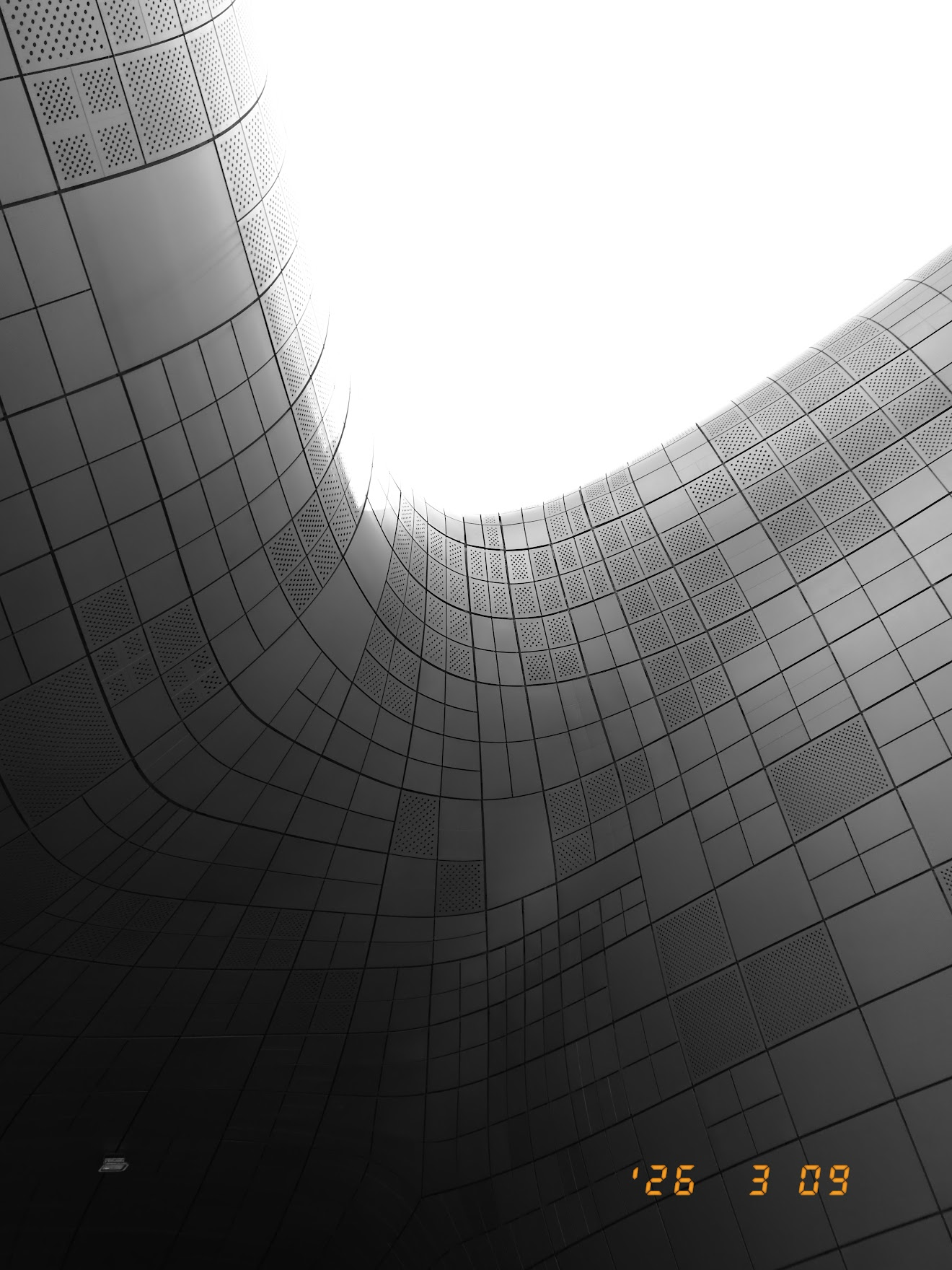 DDPの外壁を真下から見上げた構図。銀色のパネルが有機的な曲線を描きながら空へと続いていく幾何学的な美しさ