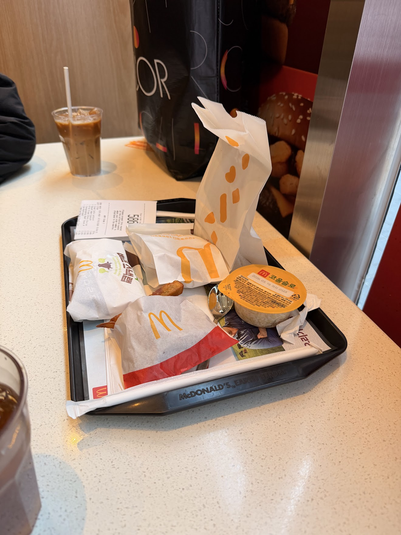 韓国のマクドナルドで注文したトレー。バーガーやサイドメニューの包装が並び、横にはアイスコーヒーが置かれている。日本にはないメニューも
