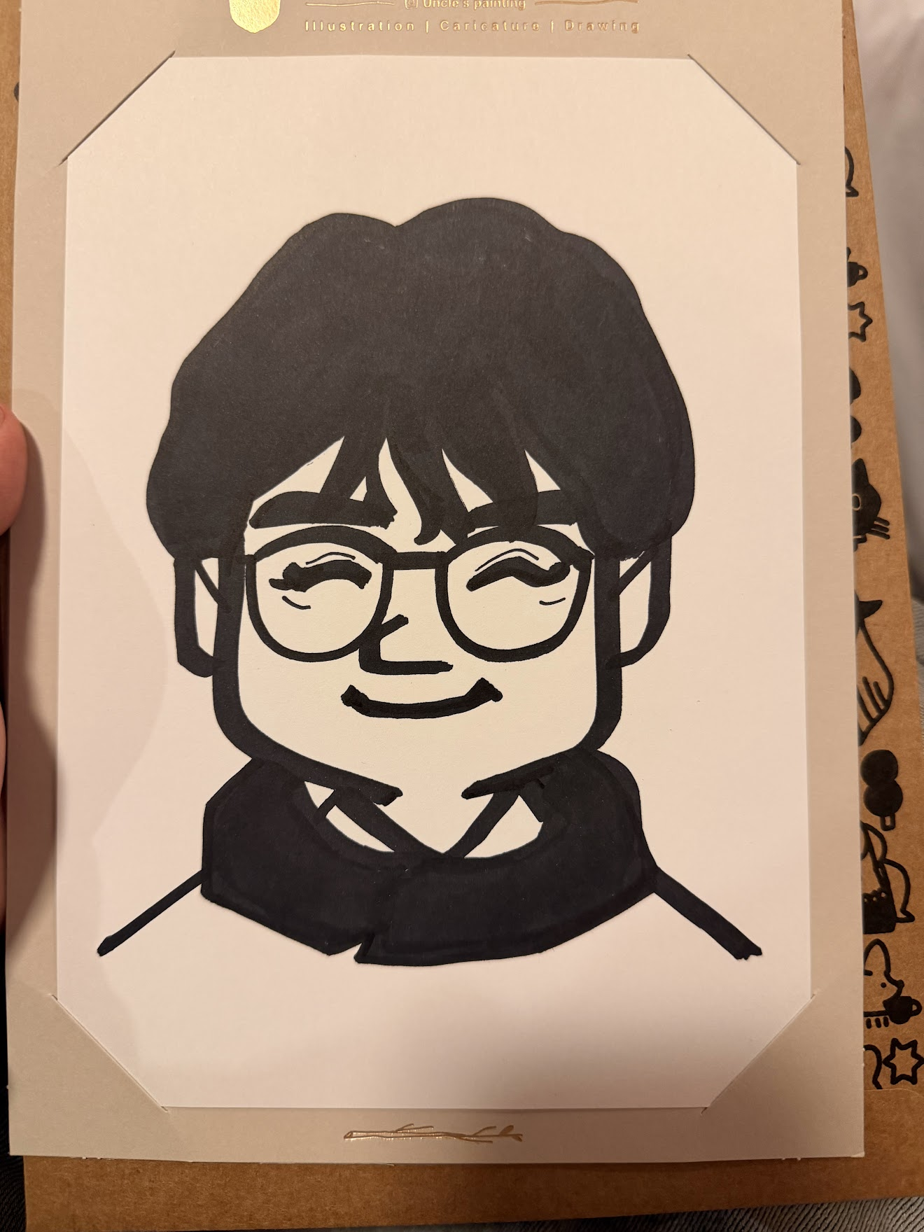 明洞の路上で描いてもらった白黒の似顔絵イラスト。丸メガネをかけた笑顔が墨の太い線で表現されている