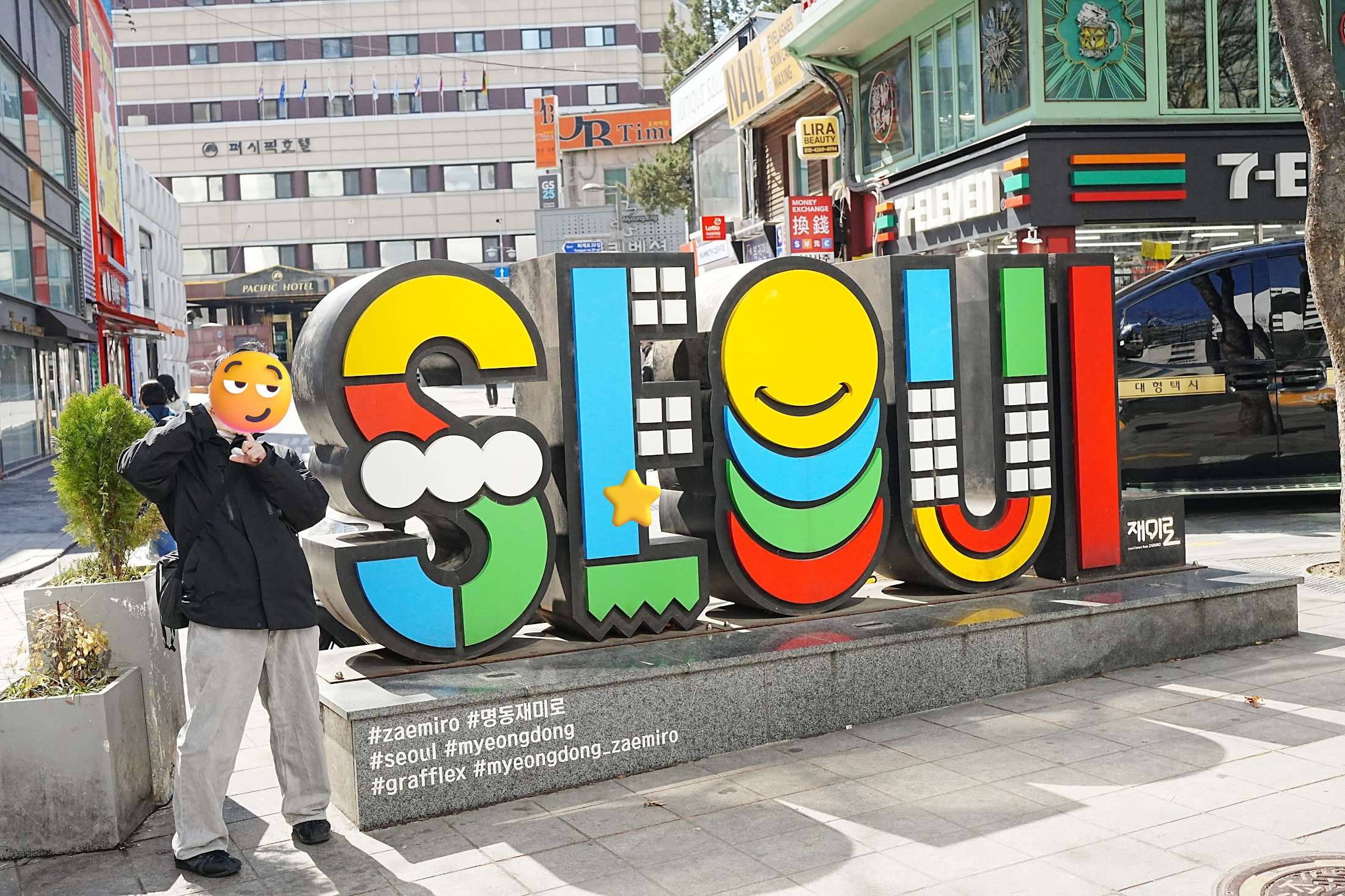 明洞の街角にあるカラフルなSEOULの立体モニュメントの横でピースサインをして記念撮影。文字は黄・緑・赤・青のポップなカラーリング